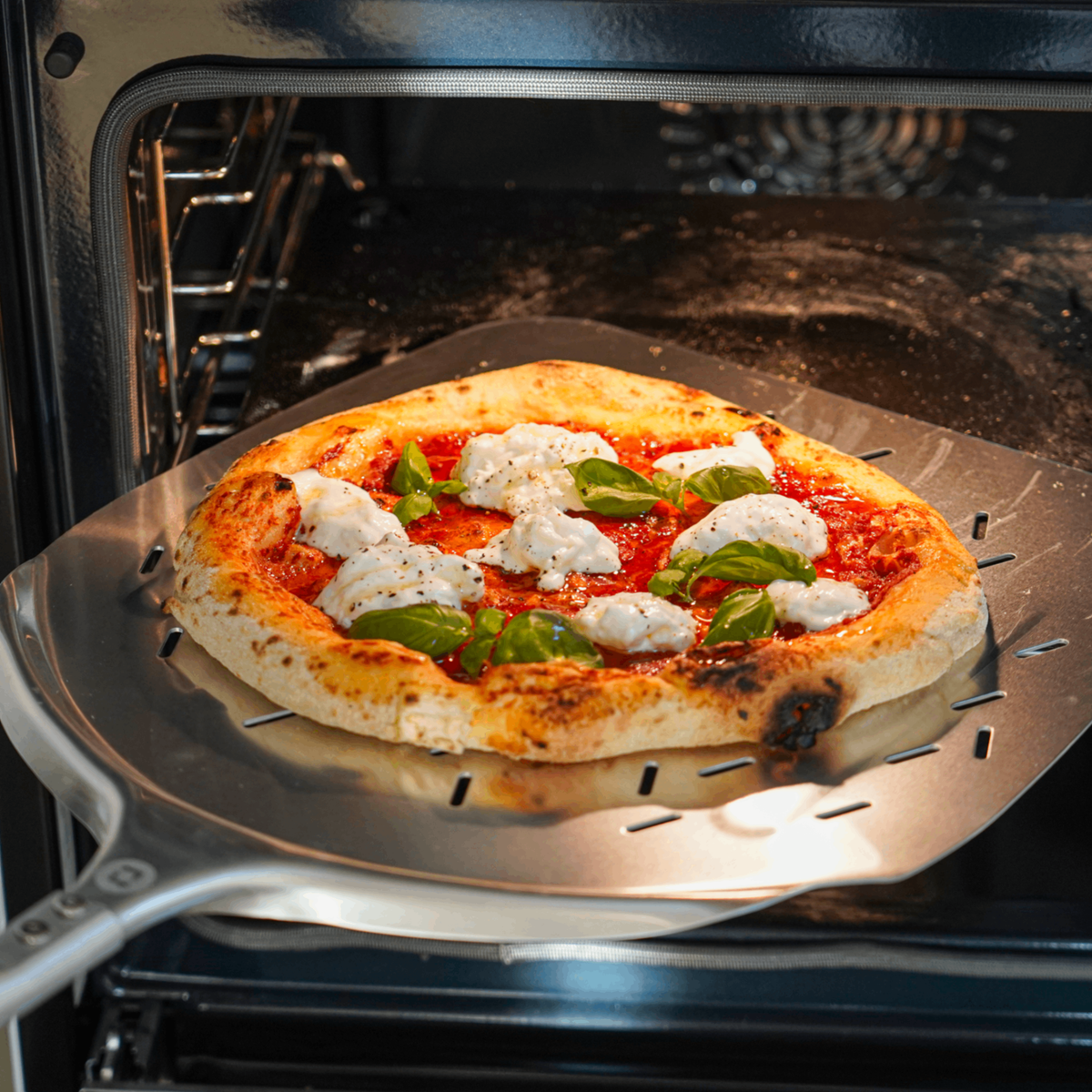 Pizza wird auf dem Pizzaschieber in den Ofen geschoben