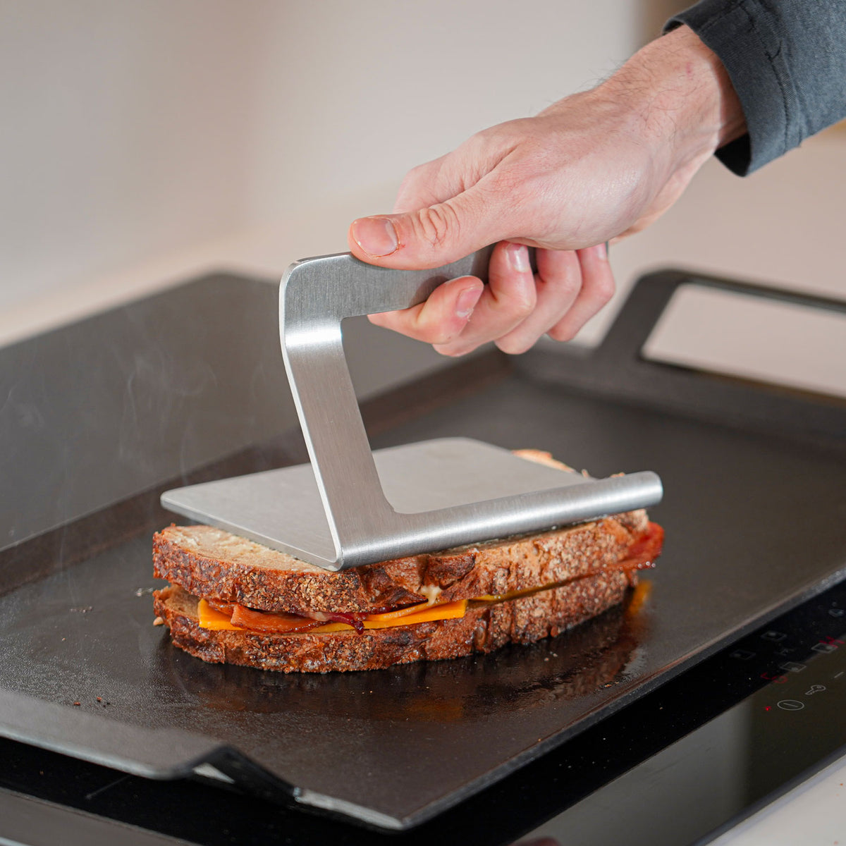 Smasher presst ein Sandwich auf der Grillplatte