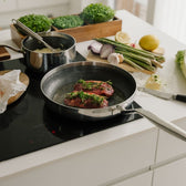 Bratpfanne mit Steaks auf dem Induktionsherd