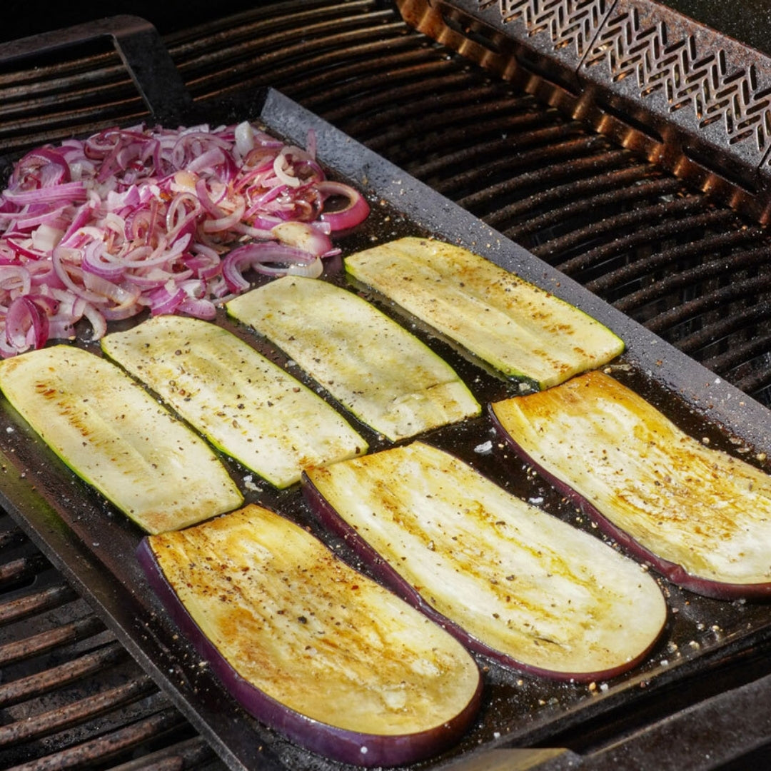Rote Zwiebeln und Aubergine auf einer Grillplatte auf dem Grill